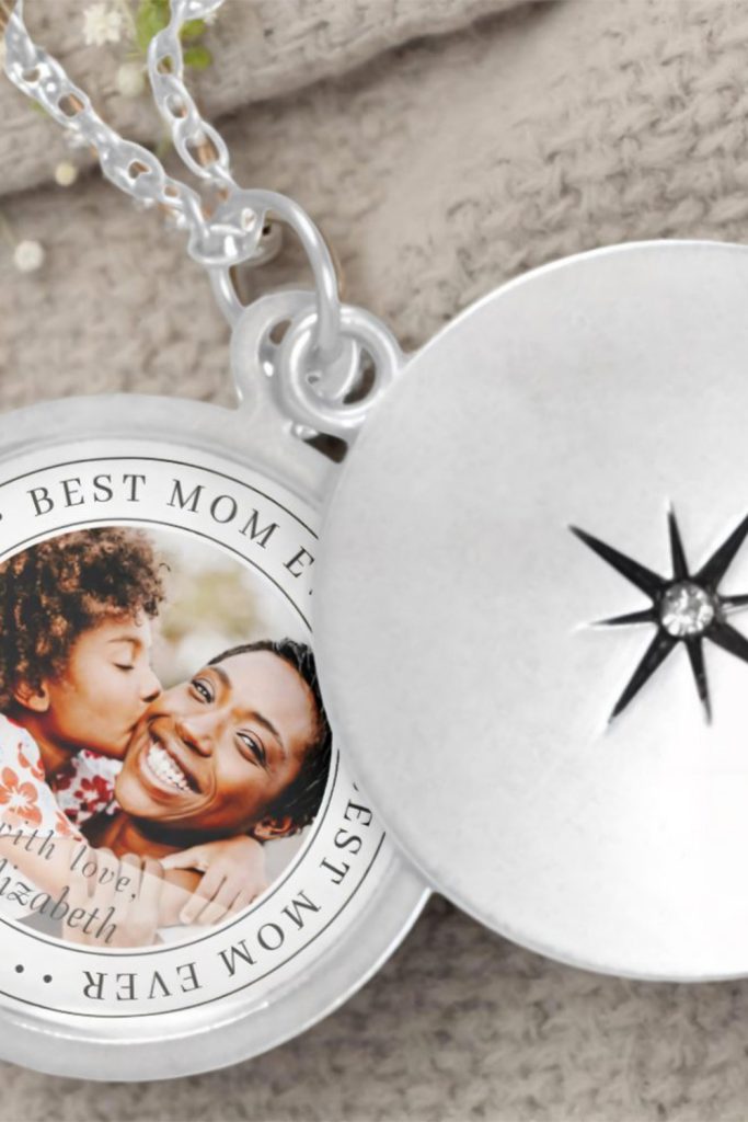 Close-Up Of A Silver Locket Necklace With A Photo Of A Mom And Child Inside, Engraved With “Best Mom Ever” And A Personal Message.