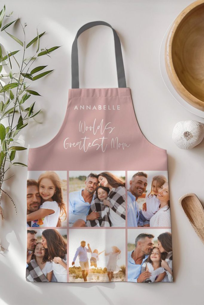 Blush Pink Apron With “World’s Greatest Mom” Text, Personalized Name, And A Collage Of Family Photos—Displayed On A Modern Kitchen Surface.
