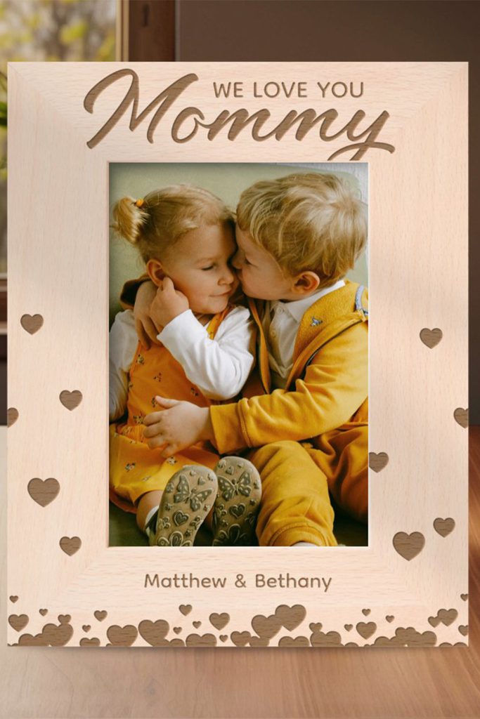 Wooden Photo Frame With Heart Engravings And The Text “We Love You Mommy,” Featuring A Personalized Name And A Sweet Photo Of Two Young Children.
