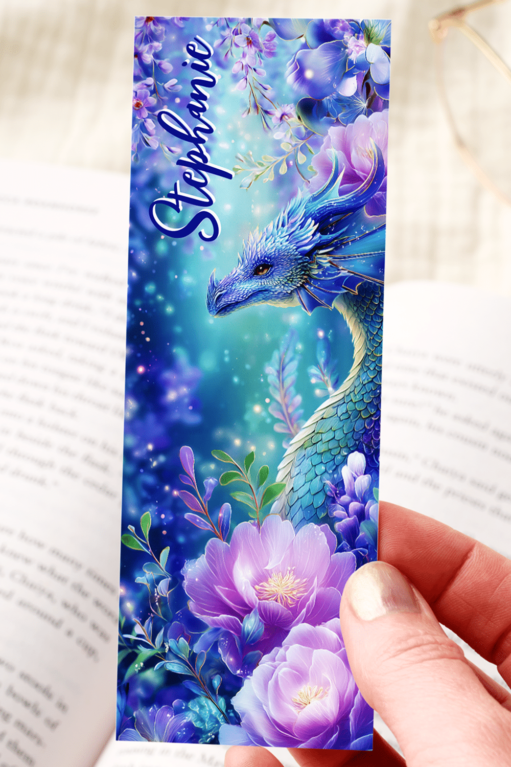 Fantasy Bookmark Featuring A Regal Blue Dragon Nestled Amidst Purple And Lavender Blossoms With Glowing Sparkles And Butterflies.