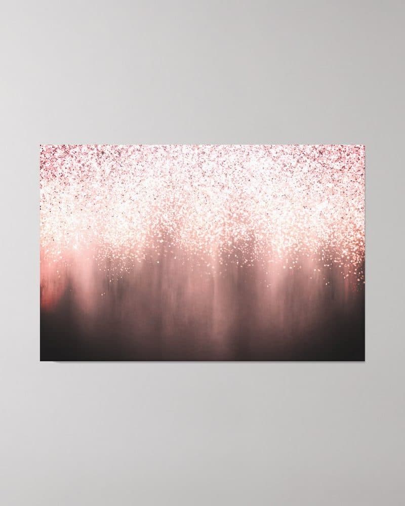 Rose gold glitter falling onto a dark background.