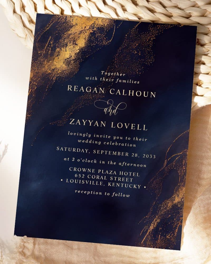 Navy blue wedding invitation with gold detailing, announcing the marriage of Reagan Calhoun and Zayyan Lovell.