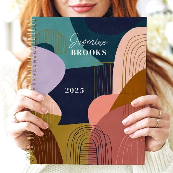 Person Holding A 2025 Planner With An Abstract Design Featuring Muted Colors And Gold Accents. The Planner Is Personalized With The Name Jasmine Brooks.