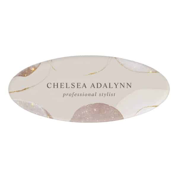 Oval Name Tag For Chelsea Adalynn, Professional Stylist; Features A Beige Background With Abstract Shapes And Gold Accents.
