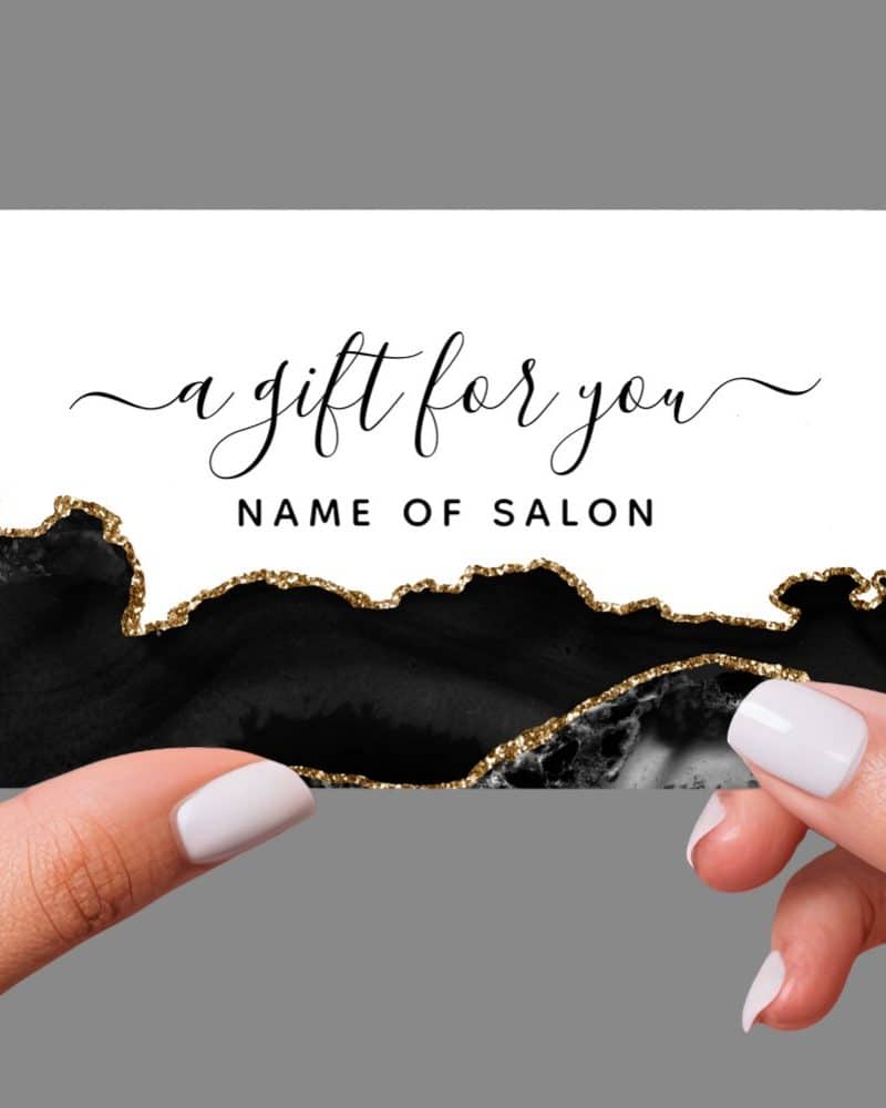 Hands holding a black and gold gift certificate with elegant script that says a gift for you.