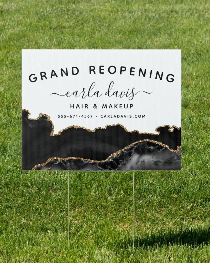 Grand reopening sign for Carla Davis Hair & Makeup. The sign features a black and gold design.