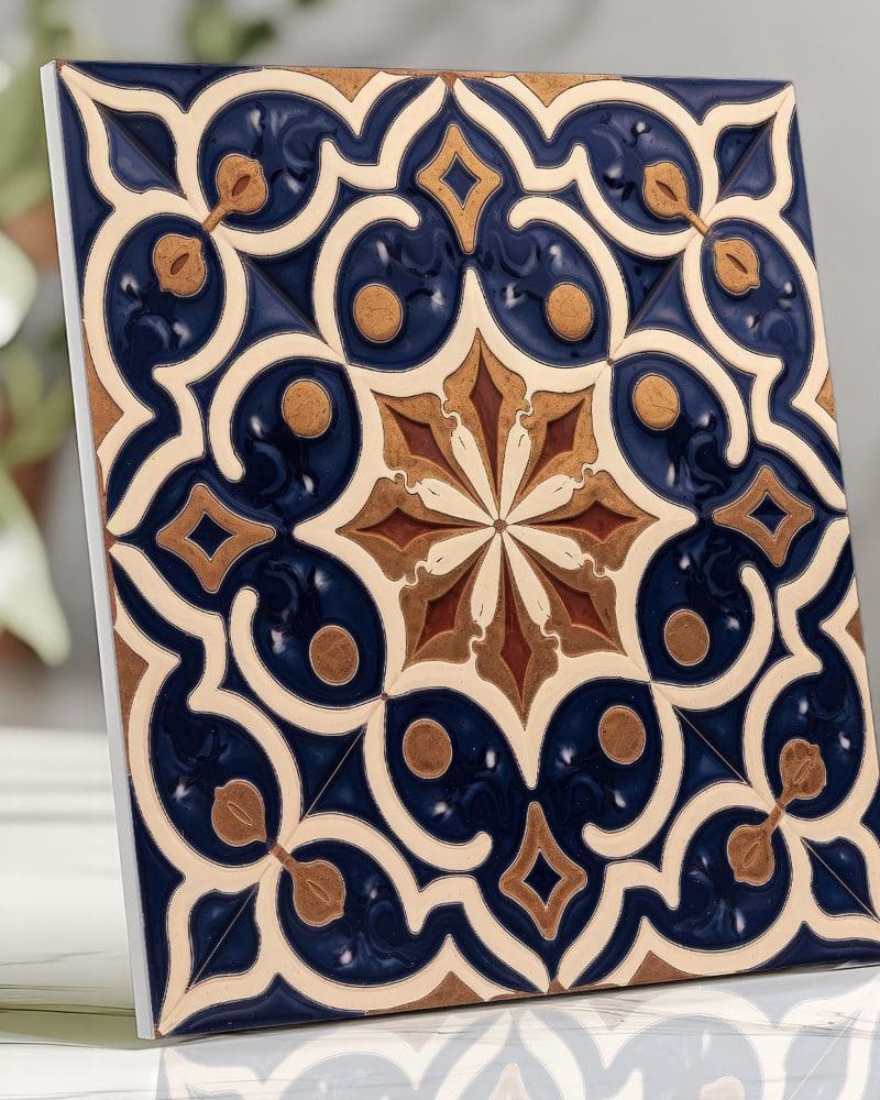 Square tile with an ornate blue, beige, and brown geometric pattern.