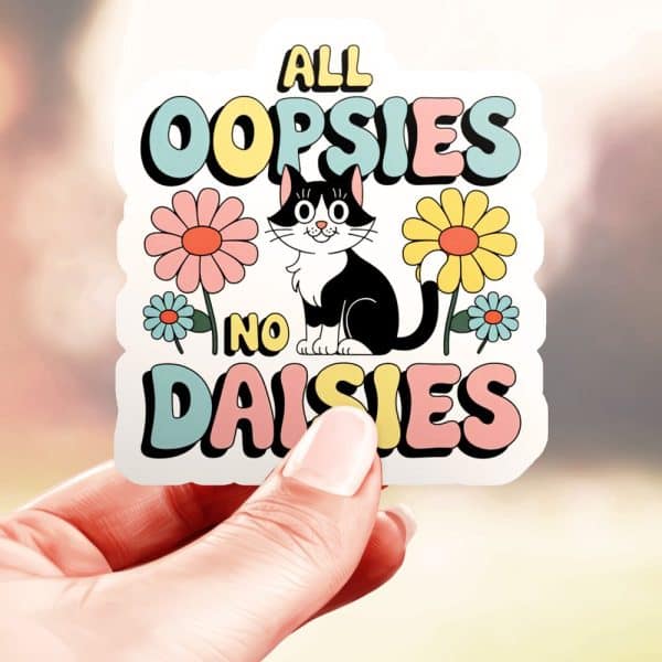 A Hand Holds A Sticker Featuring A Cartoon Tuxedo Cat Sitting Amidst Flowers, With Text Reading All Oopsies No Daisies.