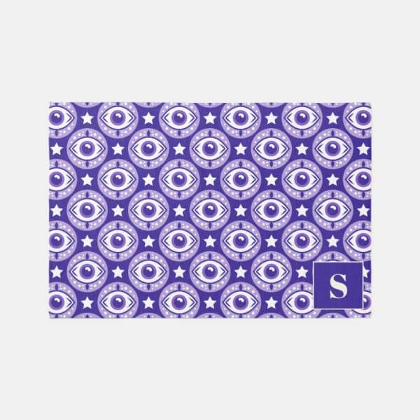 Purple Doormat With Repeating Pattern Of Eyes And Stars, And The Letter S In The Bottom Right Corner.