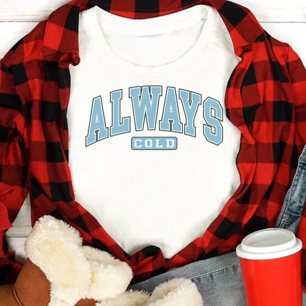 White T-Shirt With Light Blue Text That Says Always Cold In A Varsity-Style Font.