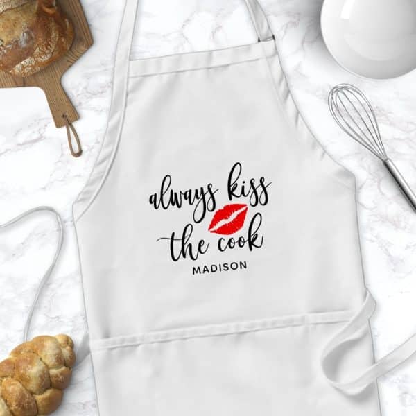 White Apron With The Text Always Kiss The Cook And A Red Lip Print, Personalized With The Name Madison.