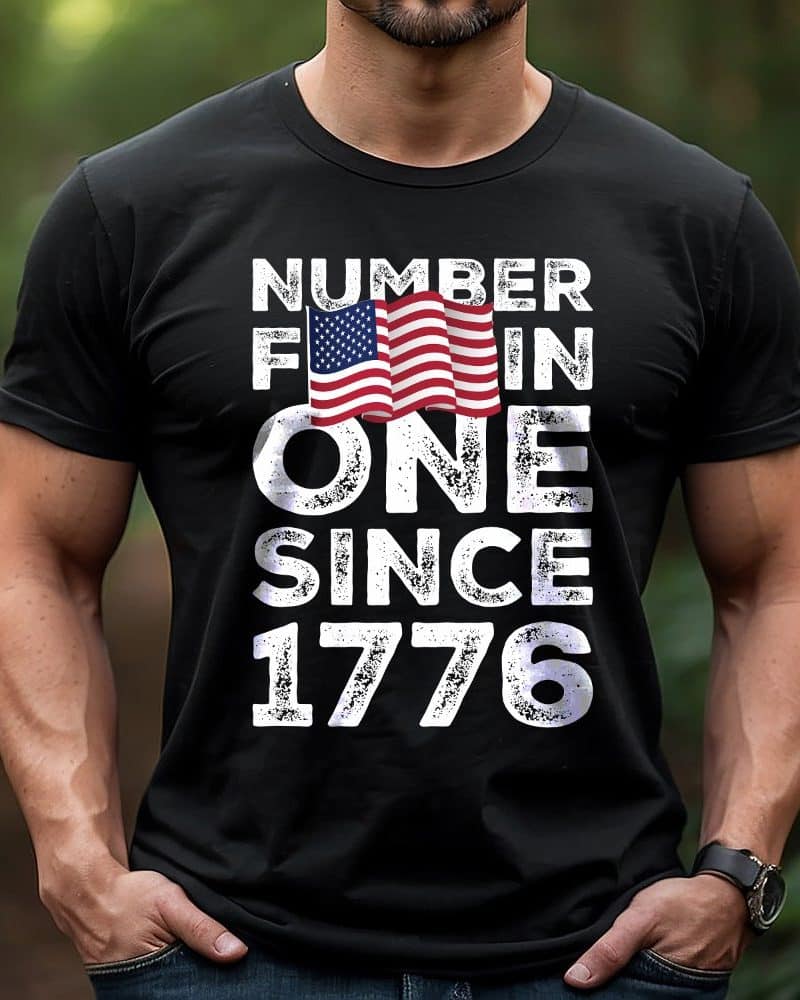 Man wearing a black t-shirt with a distressed American flag graphic and the text Number 1 Since 1776.