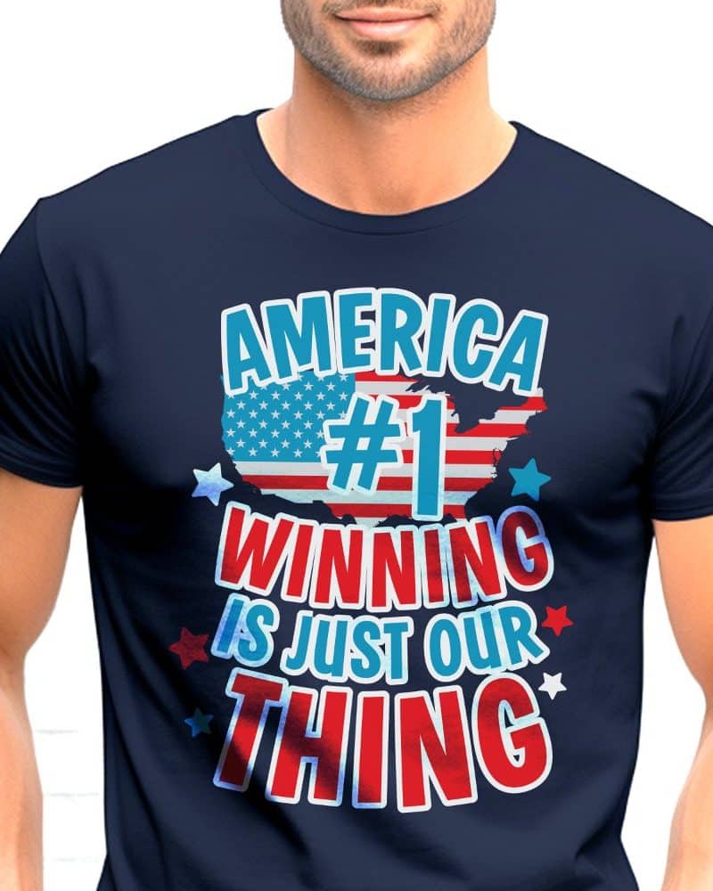 A navy blue t-shirt displaying a patriotic graphic. The design features an American flag, the number one, and the text America Winning Is Just Our Thing.