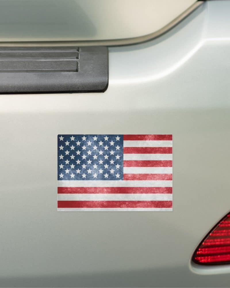 Distressed American flag sticker on a car bumper.