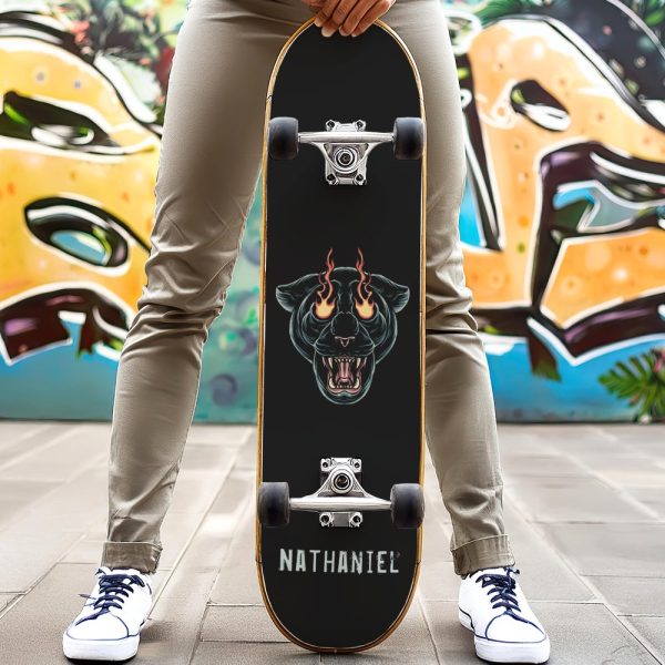 Person Holding A Black Skateboard With A Graphic Of A Snarling Black Panther With Fire In Its Eyes. The Name Nathaniel Is Printed On The Board.