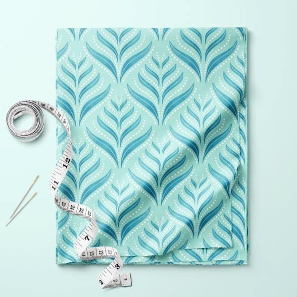 Teal Fabric With A Repeating Leaf And Dot Pattern, Accompanied By A Tape Measure And Needles.