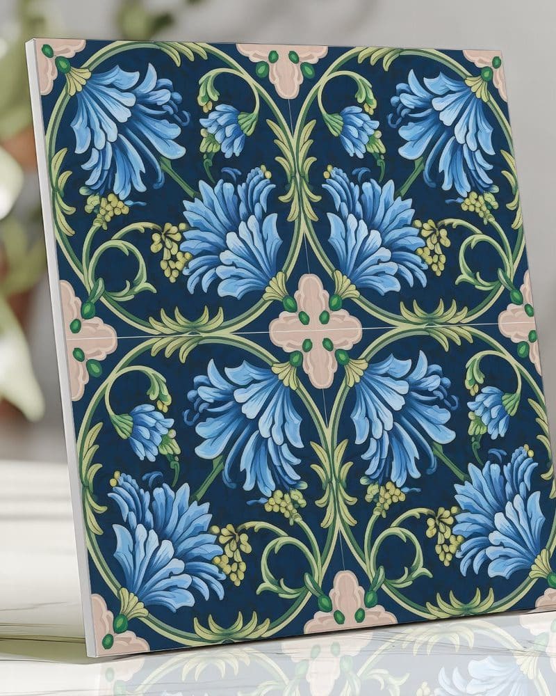 Square tile featuring a repeating pattern of stylized blue flowers and green leaves on a dark blue background.