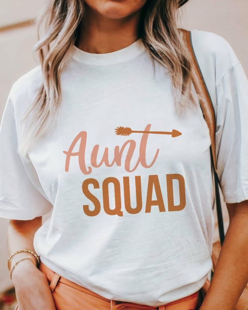 White t-shirt with the words Aunt Squad in peach and brown lettering; a small arrow graphic above the words.