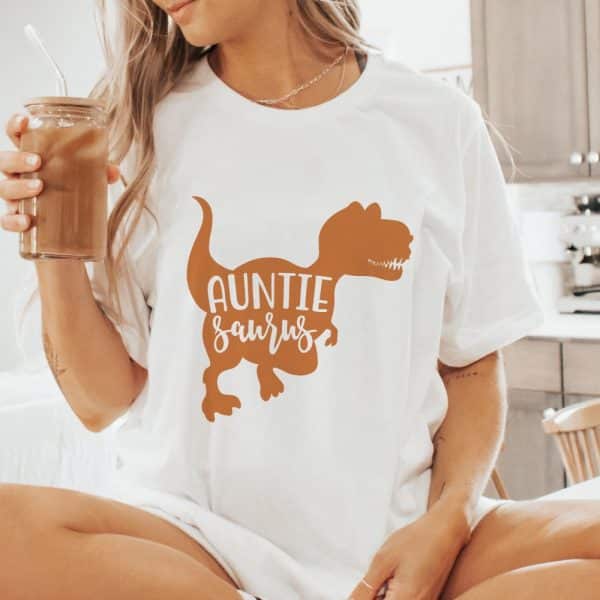 Woman Wearing A White T-Shirt With An Orange Dinosaur And The Words Auntie Saurus.