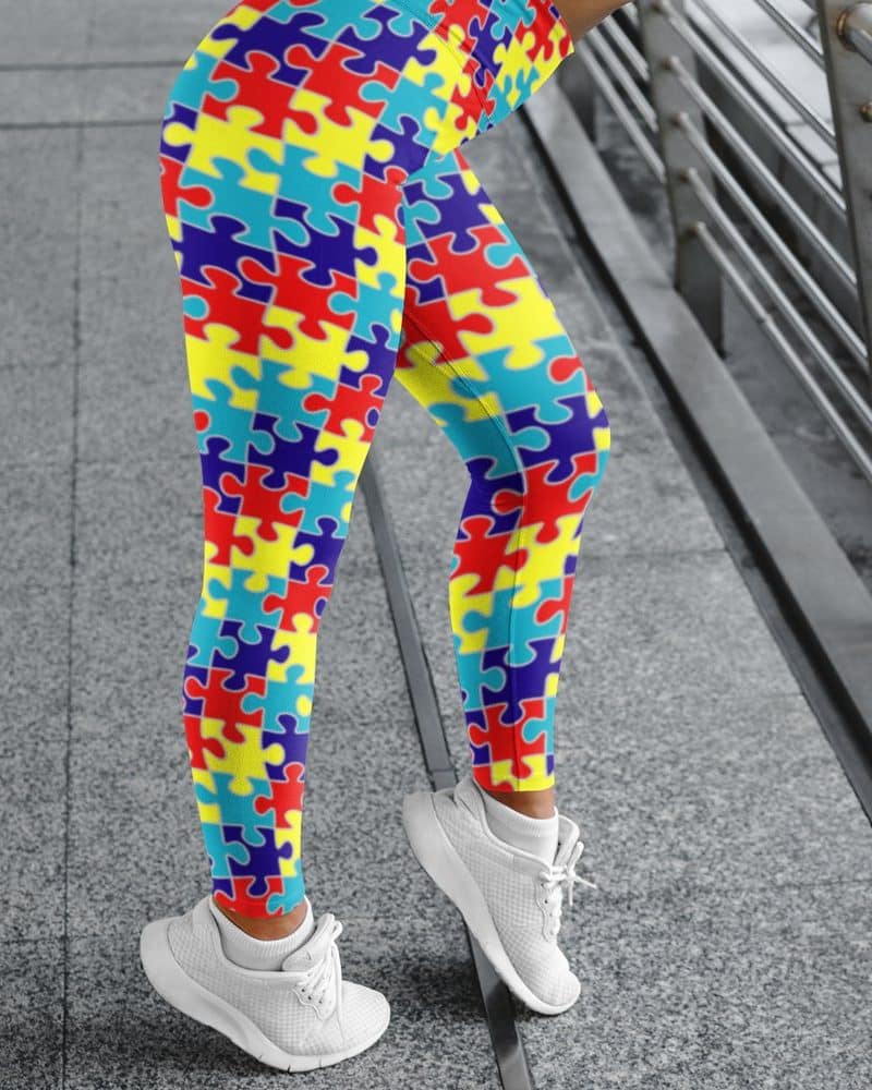 Legs wearing bright puzzle-piece patterned leggings and white sneakers.