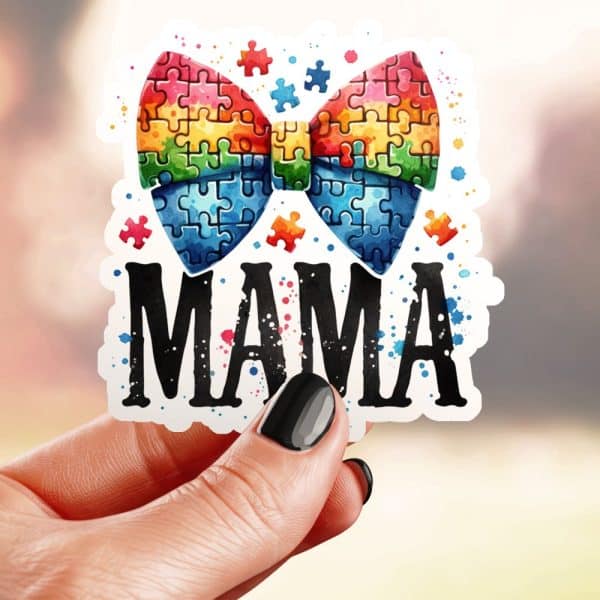 A Hand Holds A Sticker Showing A Rainbow Puzzle Piece Bow With The Word Mama Below It.