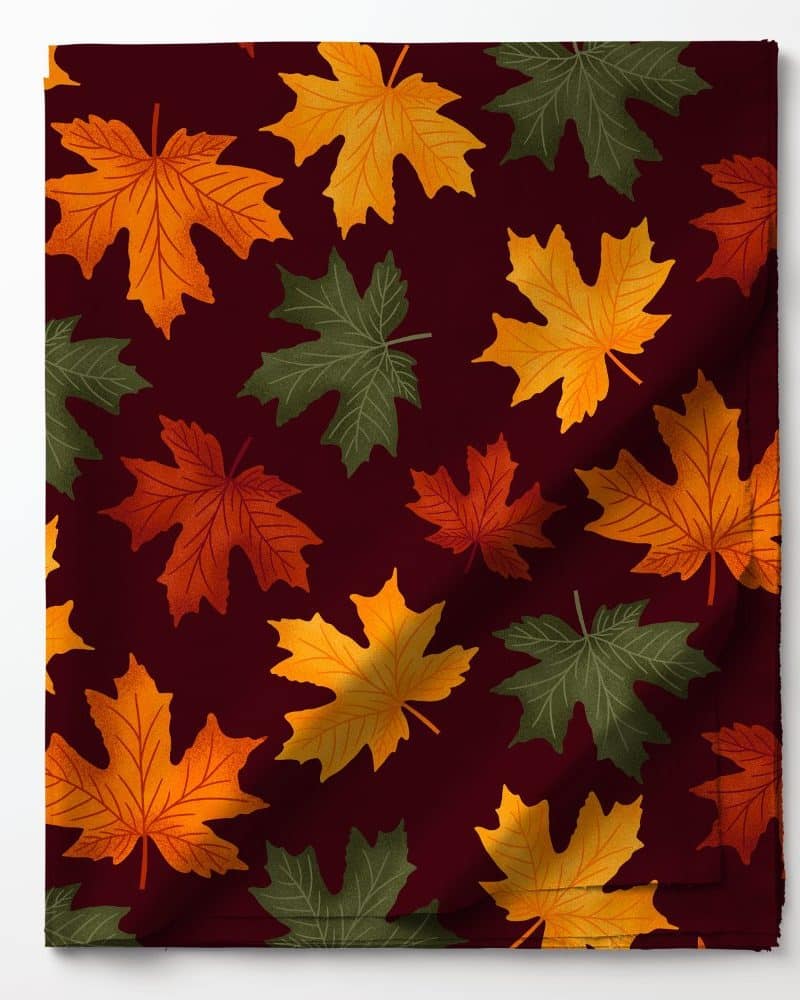 Fabric with a pattern of orange, red, and green maple leaves on a dark red background.