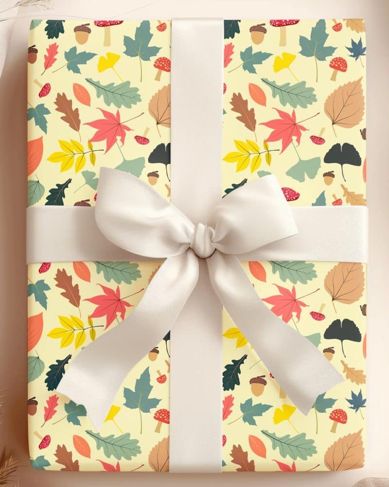 A gift wrapped in autumn-themed paper featuring leaves, acorns, and mushrooms, tied with a cream-colored ribbon.
