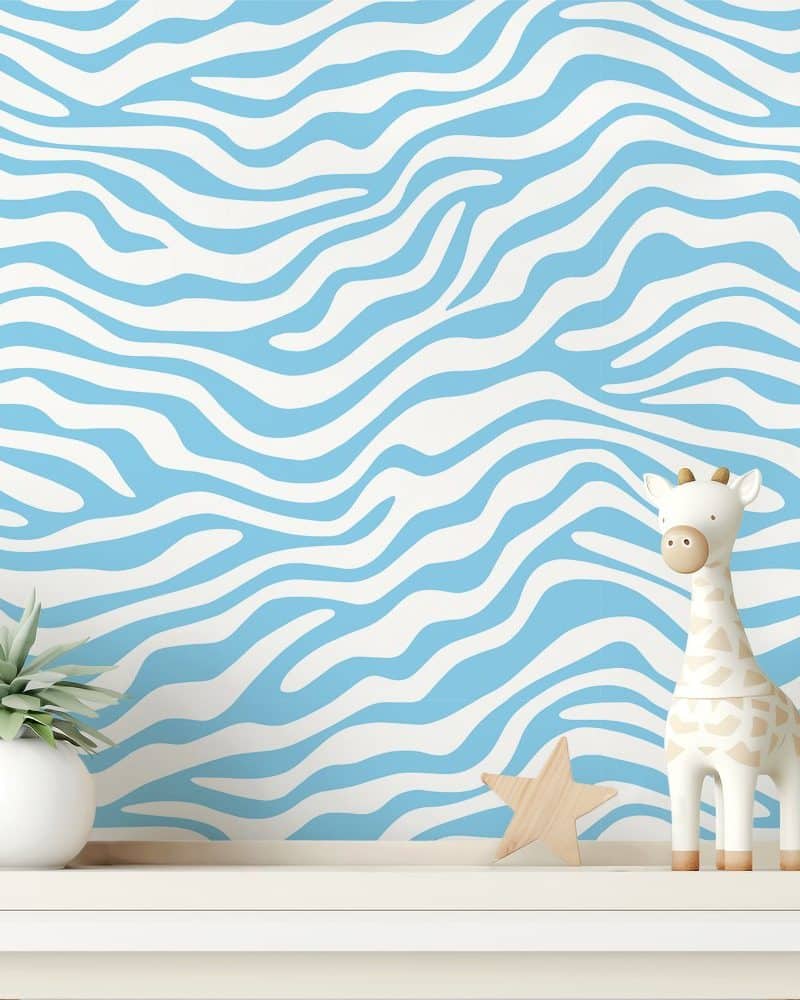 White and light blue zebra print wall with a small giraffe figurine and plant.