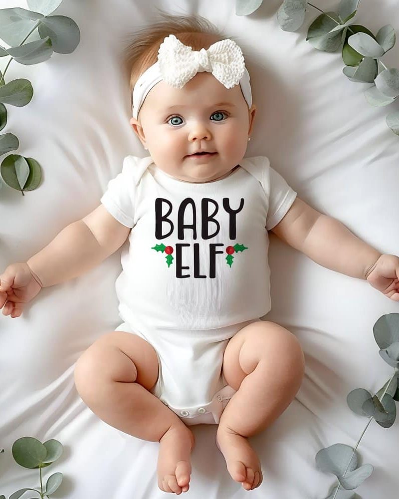 Baby wearing a white onesie that says Baby Elf.