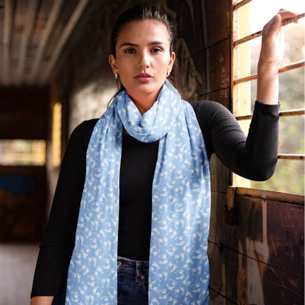 Woman Wearing A Light Blue Scarf With A White Footprint Pattern.