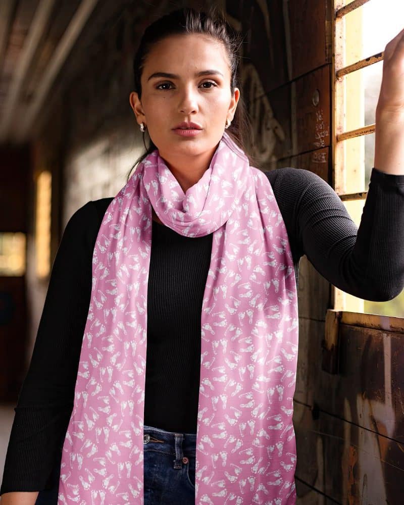 Woman wearing a pink scarf with a white footprint pattern.