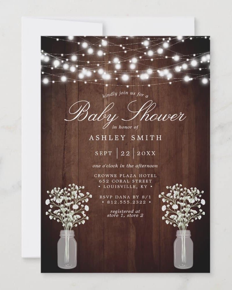 Baby shower invitation for Ashley Smith, featuring string lights and mason jars with flowers on a wood background.