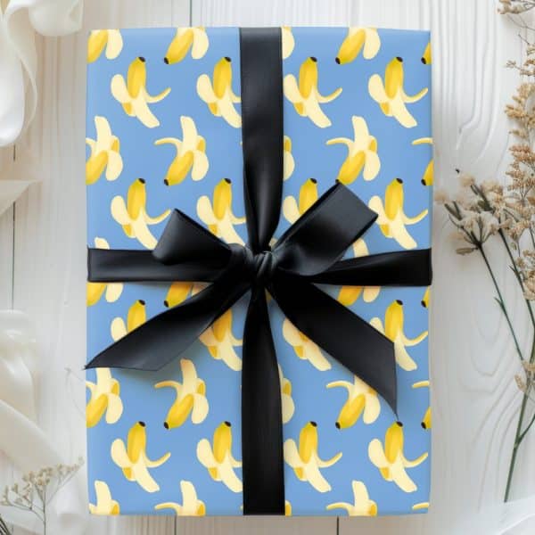 A Gift Wrapped In Light Blue Paper With A Pattern Of Peeled Bananas And Tied With A Black Ribbon.