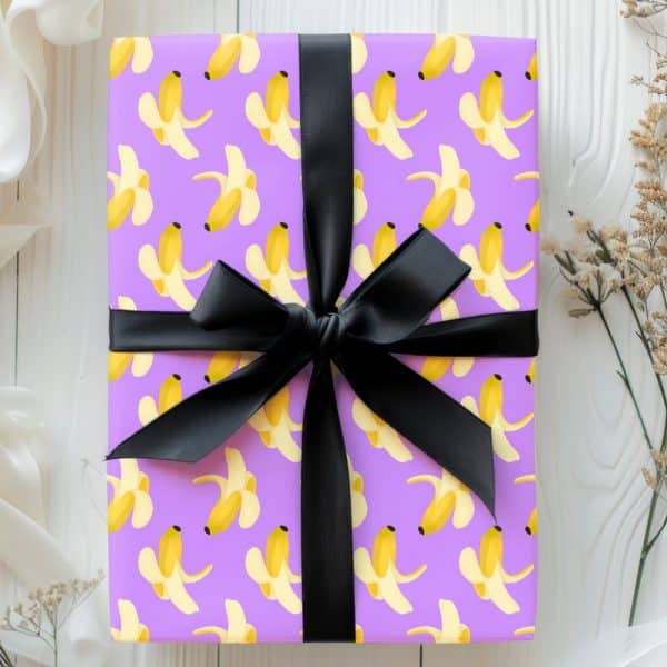 Purple Gift Box With A Black Ribbon, Wrapped In Banana Peel Patterned Paper.