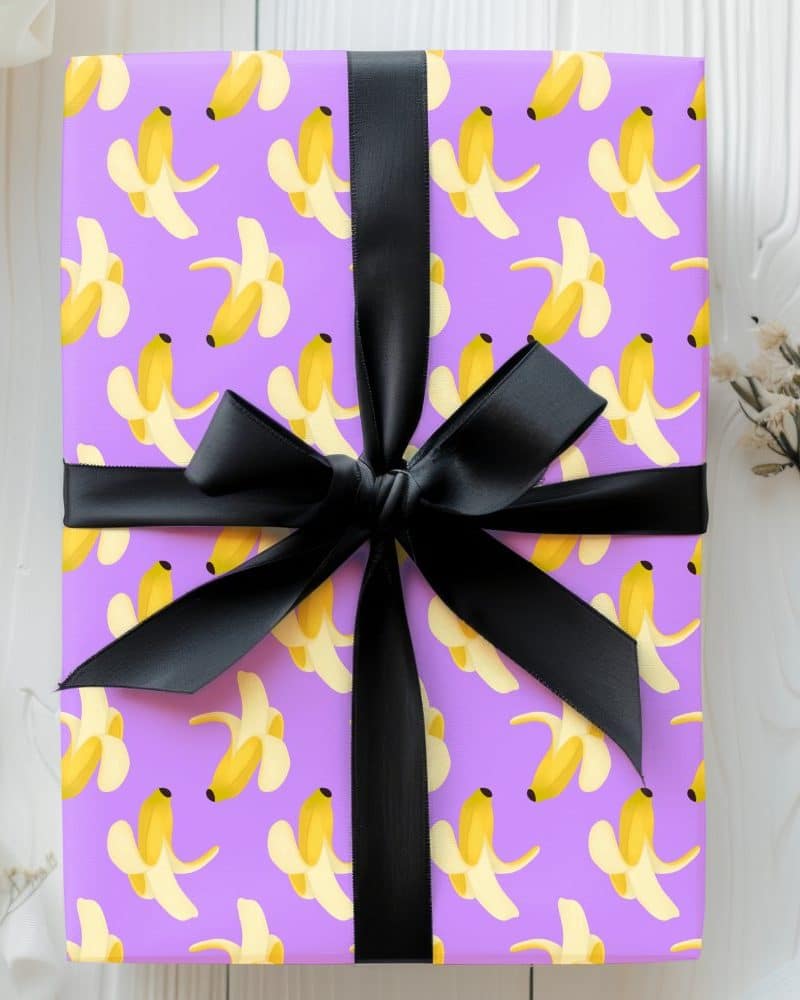 Purple gift box with a black ribbon, wrapped in banana peel patterned paper.