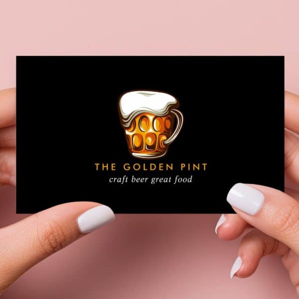 Two Hands Hold A Black Business Card Displaying A Logo: A Golden Beer Stein With Frothy Head. Below The Logo, Text Reads The Golden Pint, Craft Beer Great Food.