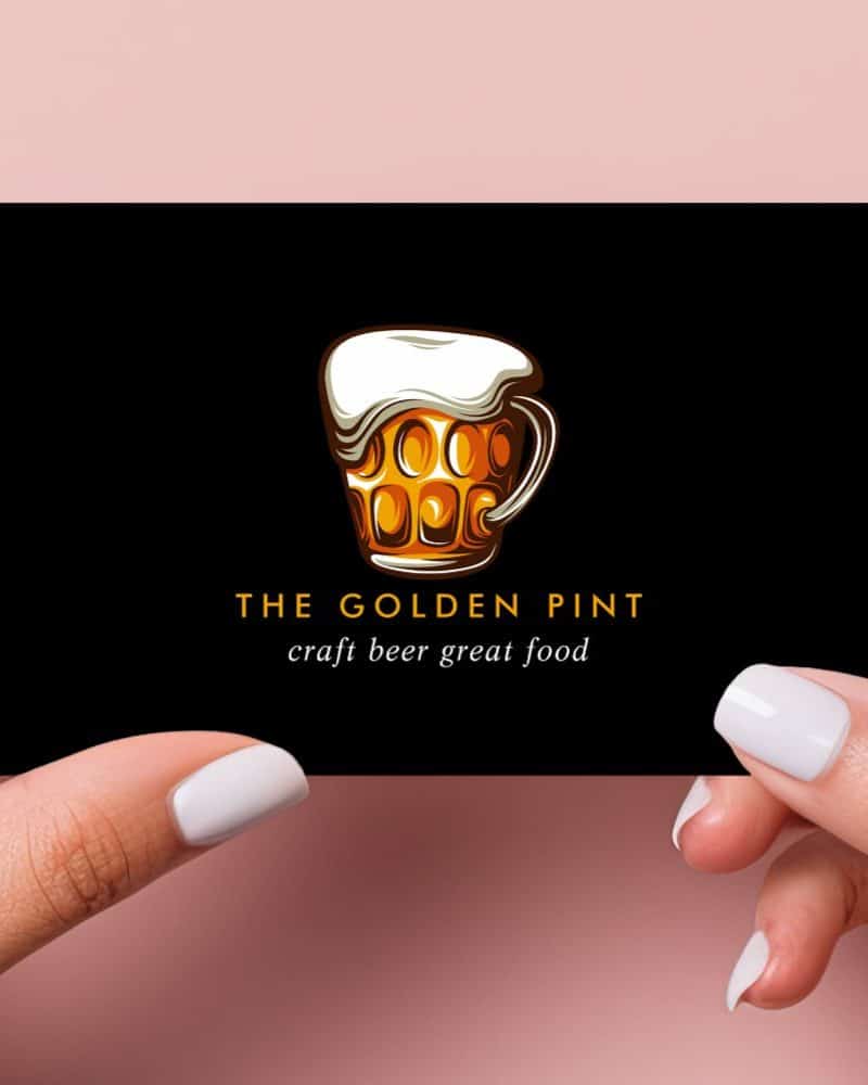 Two hands hold a black business card displaying a logo: a golden beer stein with frothy head. Below the logo, text reads The Golden Pint, craft beer great food.