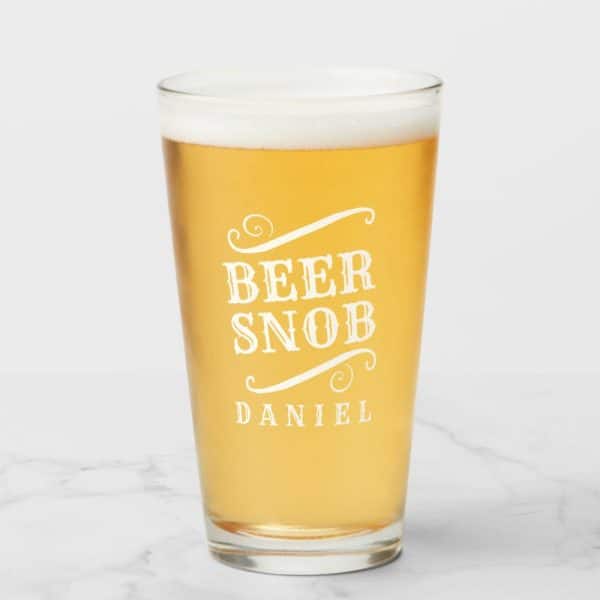 A Pint Glass Of Beer With Beer Snob And Daniels Name Etched On It.