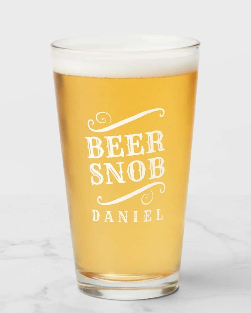 A pint glass of beer with Beer Snob and Daniels name etched on it.