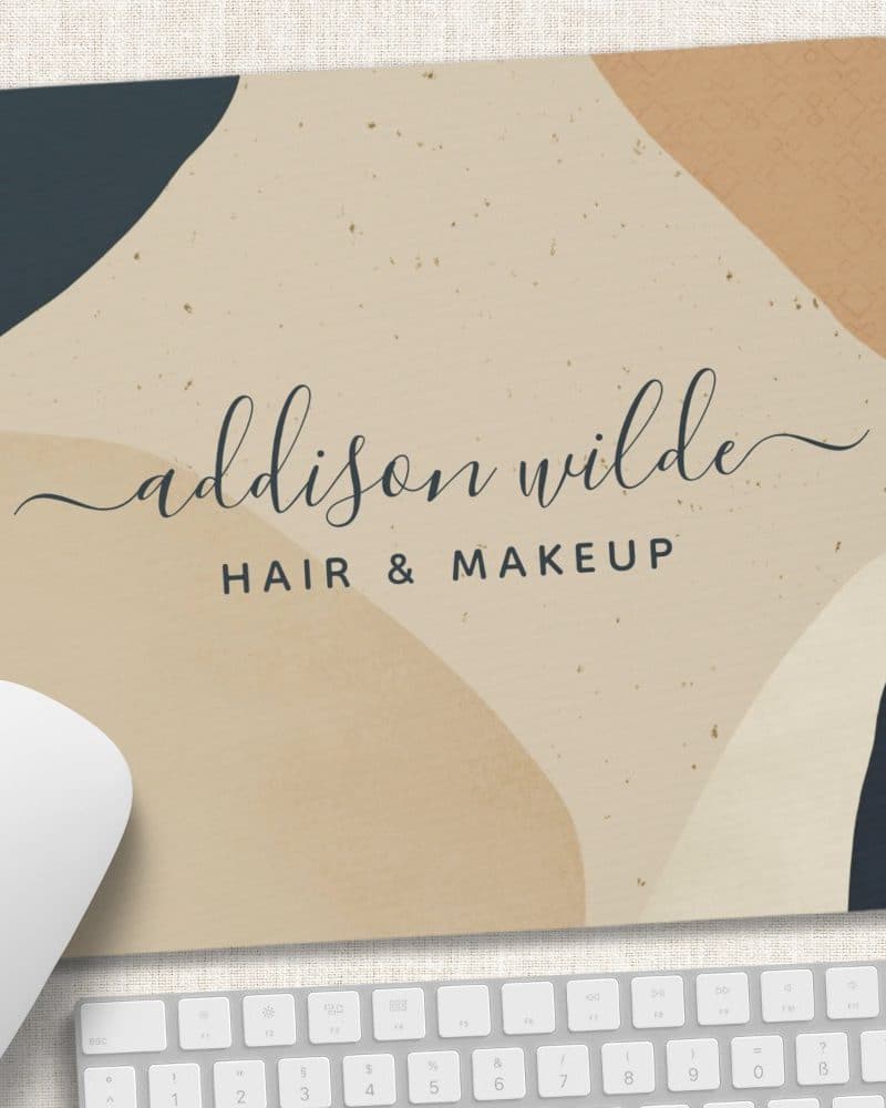 Mousepad with abstract beige and dark blue shapes and the text Addison Wilde Hair & Makeup.