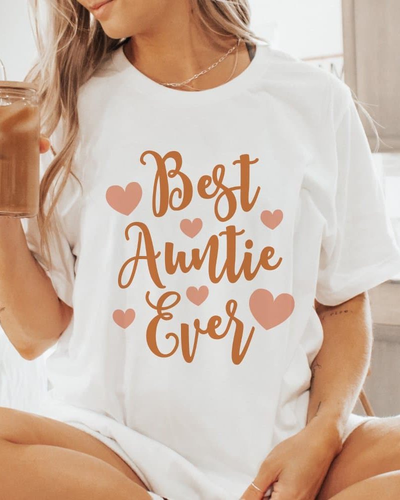 Woman wearing a white t-shirt that says Best Auntie Ever in orange lettering with pink hearts.