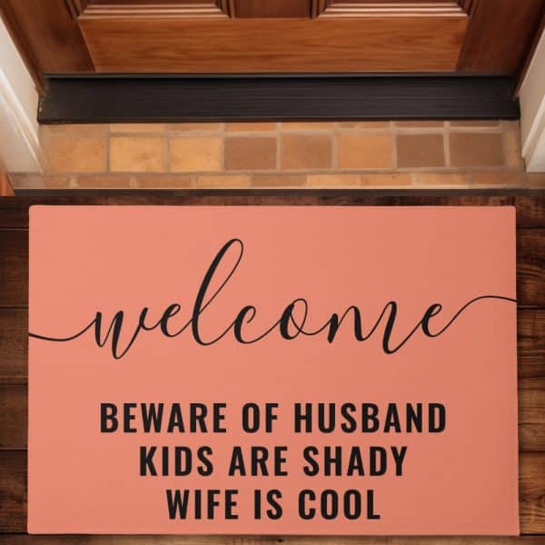 Coral Welcome Mat With Black Lettering That Says Welcome, Beware Of Husband, Kids Are Shady, Wife Is Cool.