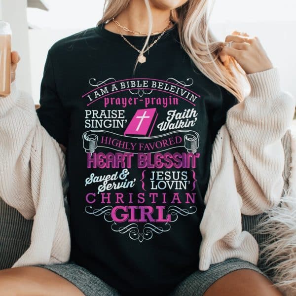 Woman Wearing A Black T-Shirt With Pink Lettering That Says Christian Girl And Includes Other Religious Phrases.