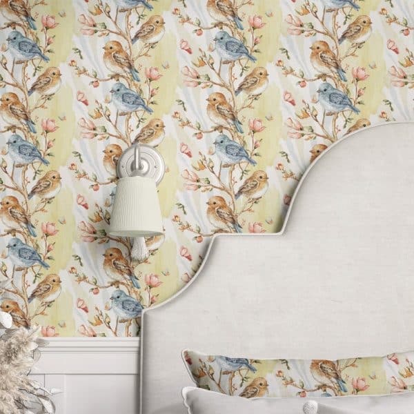 A Pale Yellow Wallpaper Featuring Watercolor Birds On Branches With Pink Flowers, Partially Visible On A Bedroom Wall And Headboard.