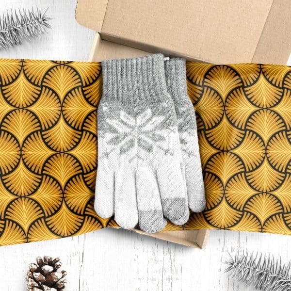 A Pair Of Grey And White Knit Gloves With A Snowflake Pattern, Inside A Gift Box Lined With Gold Patterned Paper.