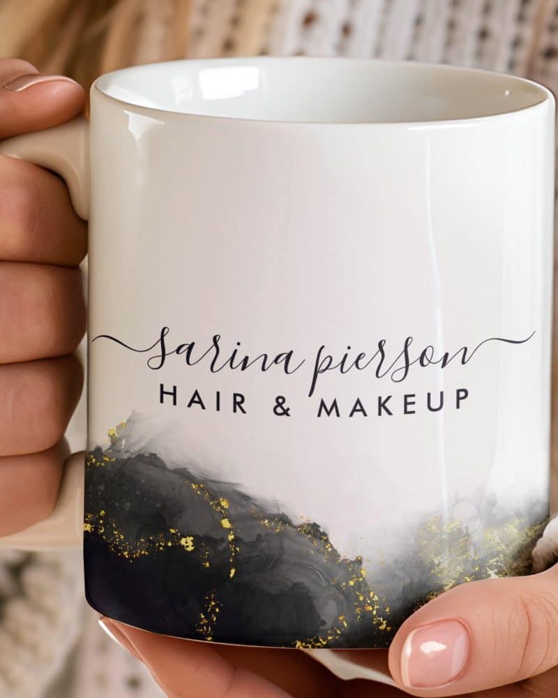 White coffee mug with the name Sarina Pierson Hair & Makeup and a gray and gold design.