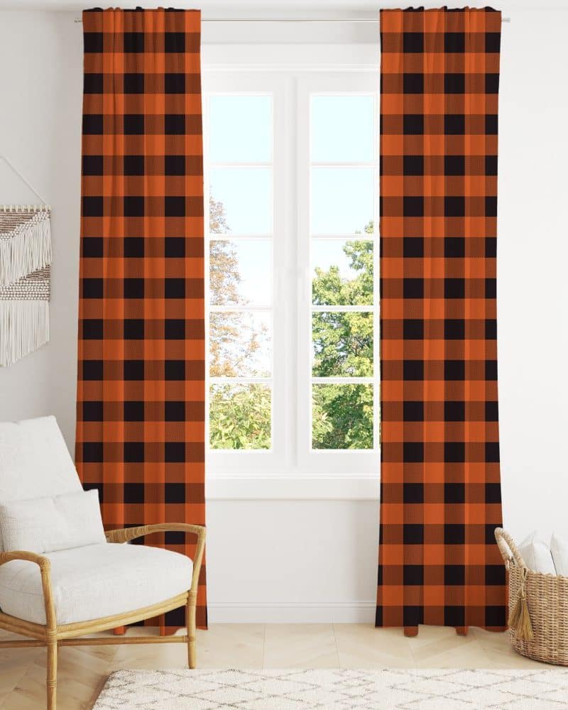 Orange and black buffalo plaid curtains hanging in a window.