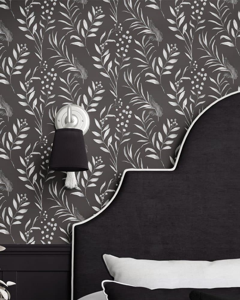 Dark gray bedroom wall with a white floral wallpaper pattern and a black headboard.