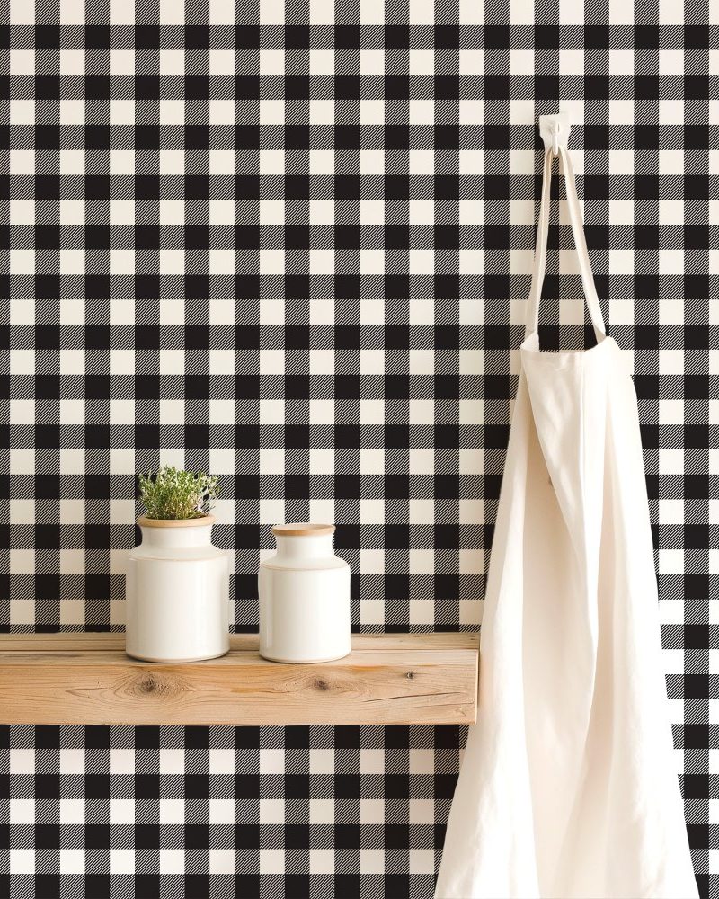 Black and white buffalo check wallpaper with a wooden shelf holding two white containers and a white apron hanging on a hook.
