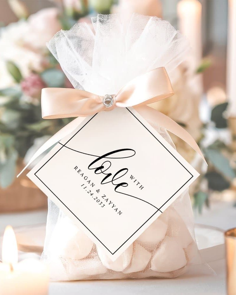 Wedding favor bag with white tulle, a beige ribbon, and a small square tag that says Love with the couple's names and wedding date.